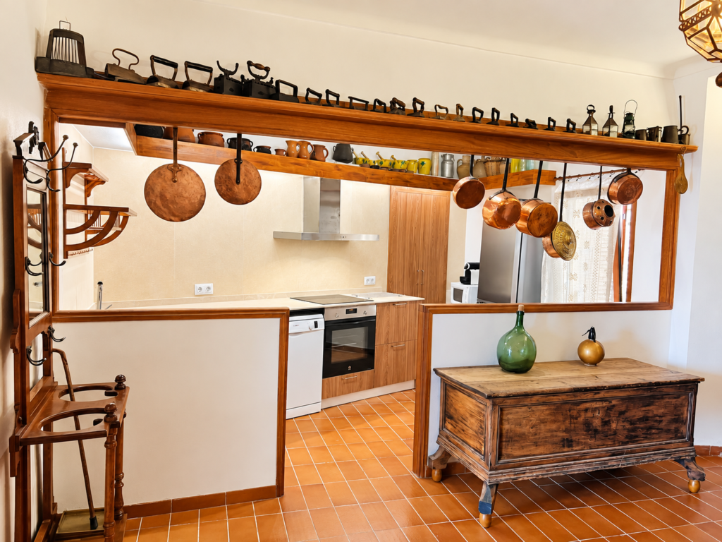 Cocina equipada de estilo tradicional mallorquín con detalles en madera y cobre en una casa vacacional en Campanet.