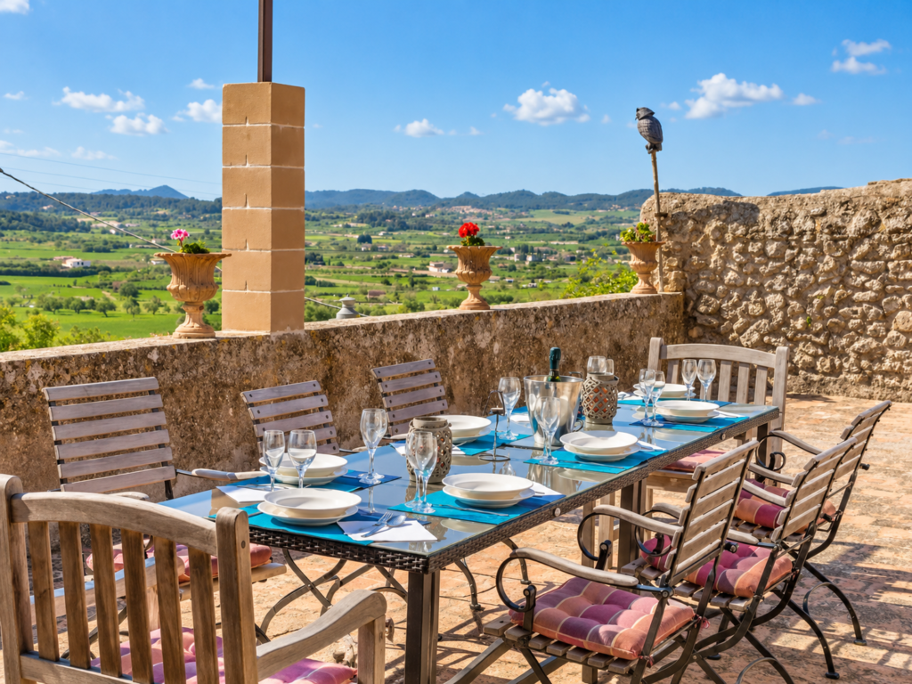 Terraza exterior con mesa comedor y vistas al campo en una finca vacacional en Mallorca, perfecta para comidas al aire libre.