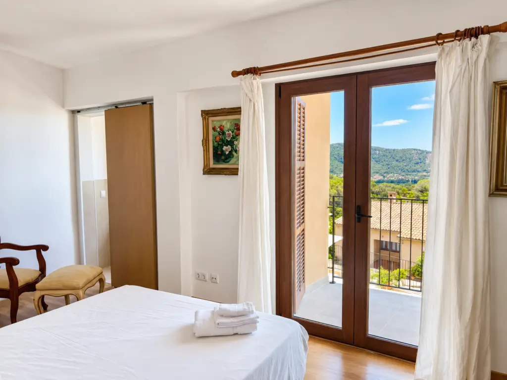 Dormitorio luminoso con acceso a terraza y vistas a la montaña en una casa tradicional mallorquina en Campanet.
