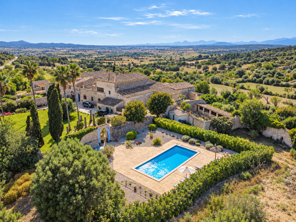 Vista panorámica de una finca rural en Mallorca con piscina privada, jardines y amplias vistas al paisaje mallorquín.