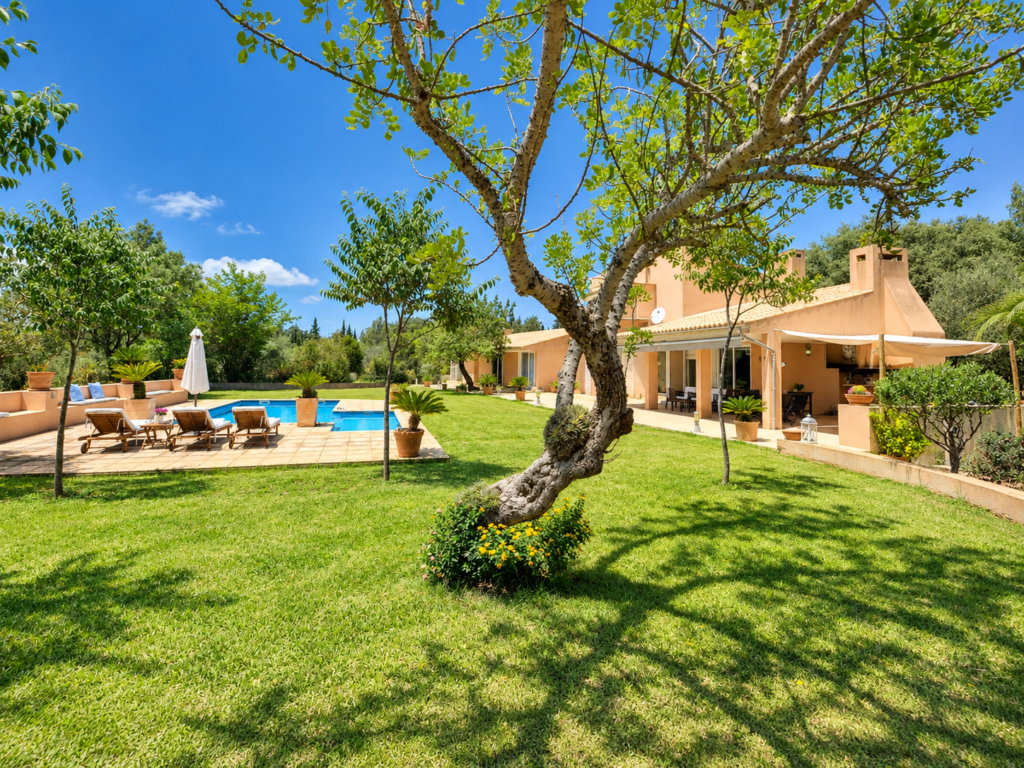 Amplio jardín privado con césped, árboles y piscina en una casa vacacional en Bunyola, cerca de la Serra de Tramuntana.