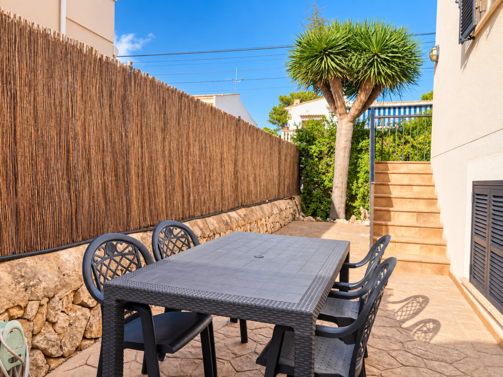 Terraza exterior con mesa y sillas en un adosado vacacional situado a pocos minutos a pie de la playa en Colònia de Sant Jordi.