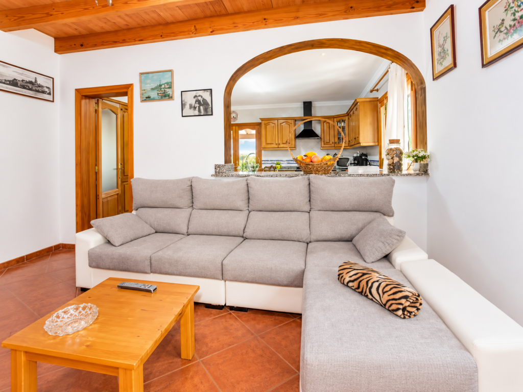Salón amplio con sofá y cocina abierta en una villa vacacional en Lloseta, Mallorca, pensada para familias.