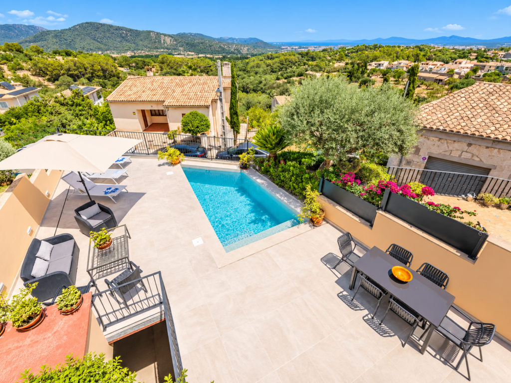 Terraza exterior con piscina privada, comedor y vistas panorámicas a la montaña y al entorno de Campanet, Mallorca.