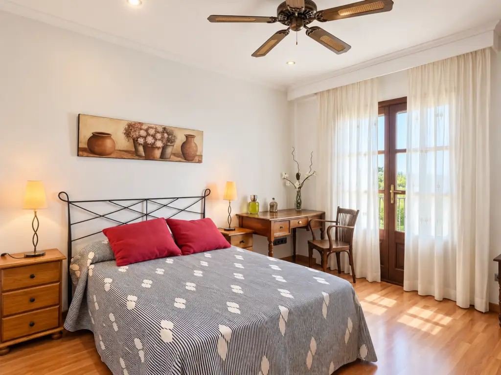 Dormitorio con cama de matrimonio, escritorio y luz natural en Ca’n Valero, finca vacacional familiar en Mallorca.