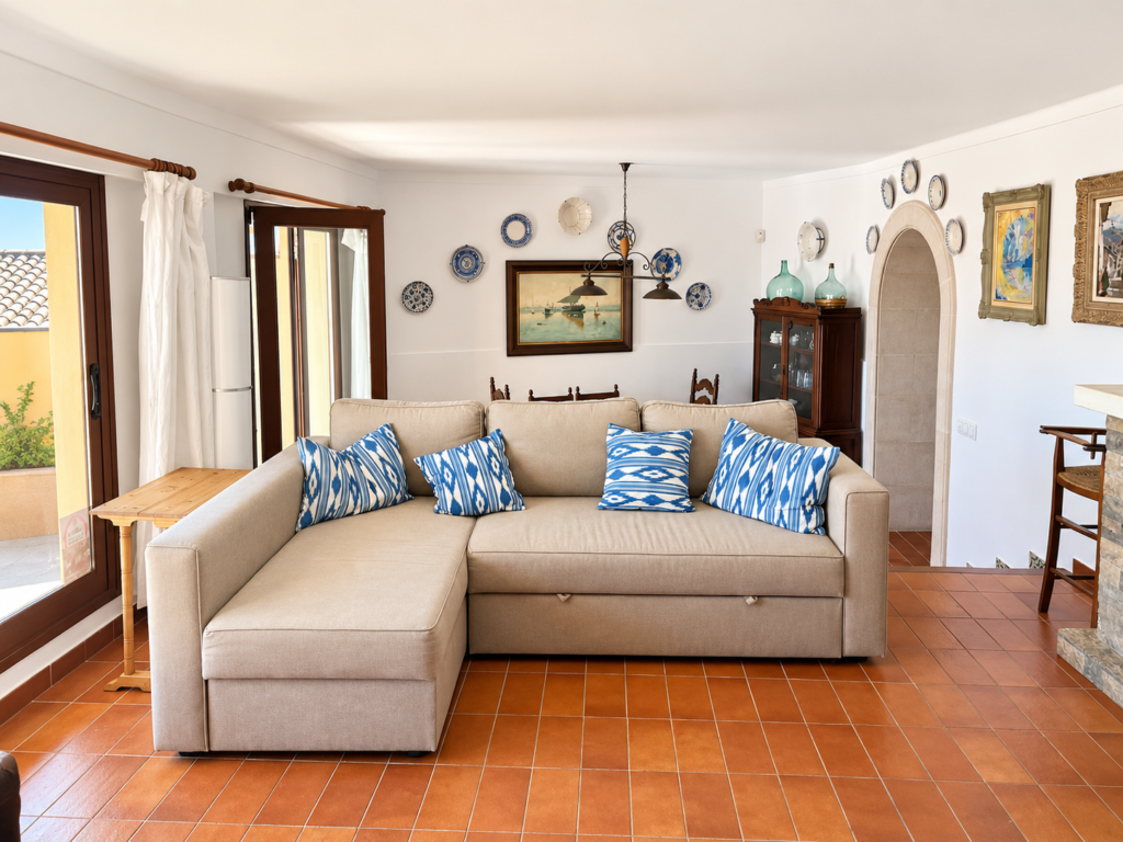 Salón acogedor de estilo mallorquín con sofá, decoración tradicional y acceso a las zonas comunes de la vivienda en Campanet.