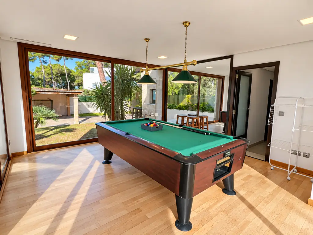 Sala de juegos con mesa de billar y grandes ventanales en Villa Bonita, villa vacacional para familias y grupos en Mallorca.